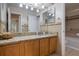 Bathroom featuring granite countertops, wood cabinets, double mirrors, and updated tile in shower at 940 Douglas Ave # 159, Altamonte Springs, FL 32714