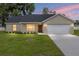 Inviting single-story home with a two-car garage, a fresh lawn, and exterior lighting at 1059 Ne 130Th Ter, Silver Springs, FL 34488