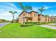 A charming view of a two-story townhome surrounded by lush green lawns and swaying palm trees at 109 Cambria Ave, Davenport, FL 33897