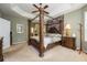 Serene main bedroom featuring a four-poster bed, tray ceilings, and ensuite bathroom at 127 Heatherbrooke Cir, Oviedo, FL 32765