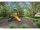 A colorful playground with a slide, climbing structures, benches, and bordered by lush trees and manicured landscaping at 127 Heatherbrooke Cir, Oviedo, FL 32765