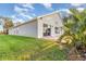 A green backyard with a stone patio and a view of the house with trees and blue skies at 1315 Vista Del Lago Blvd, Dundee, FL 33838