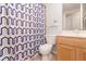 Bathroom features a toilet, vanity and shower with patterned curtain at 1315 Vista Del Lago Blvd, Dundee, FL 33838