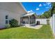 Backyard view features a screened patio, lush lawn, and a well-maintained privacy fence at 144 Bridgeton St, Davenport, FL 33896
