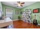 Green bedroom with modern shelving, ceiling fan, and a desk area at 144 Bridgeton St, Davenport, FL 33896