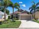 Charming home with a two-car garage, lush landscaping, and mature palm trees at 144 Bridgeton St, Davenport, FL 33896