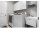 Well-lit laundry room has a utility sink, washer, dryer, and overhead storage at 144 Bridgeton St, Davenport, FL 33896