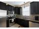 Modern kitchen featuring dark cabinets, stainless steel appliances, granite counters and a mosaic backsplash at 14845 Speer Lake Dr, Winter Garden, FL 34787