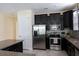 Modern kitchen boasting stainless steel appliances, dark cabinetry, granite countertops, and tile backsplash at 14845 Speer Lake Dr, Winter Garden, FL 34787