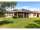 Expansive backyard featuring lush lawn, a screened lanai, and solar panels for energy efficiency at 1507 Alligator St, St Cloud, FL 34771