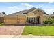 Charming single-story home featuring a brick driveway, manicured lawn, and a stone-accented entrance at 1507 Alligator St, St Cloud, FL 34771