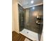 Sleek, modern shower featuring dark gray tiled walls, a glass door, and white hexagon tiled flooring at 162 Orange Pl, Maitland, FL 32751