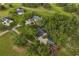 An aerial view of a blue home with a gray roof surrounded by lush trees and green grass at 16610 County Line Rd, Umatilla, FL 32784