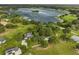 Aerial view of a home surrounded by green grass and trees, nestled on the shore of a lake at 16610 County Line Rd, Umatilla, FL 32784