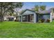 View of the home's screened-in porch and spacious backyard, surrounded by lush greenery at 16610 County Line Rd, Umatilla, FL 32784