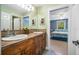 Bathroom featuring dual sinks, rustic wood cabinets, and a view of the bedroom at 16610 County Line Rd, Umatilla, FL 32784