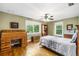 Bedroom with hardwood floors, ample lighting, a ceiling fan, and a vintage rolltop desk at 16610 County Line Rd, Umatilla, FL 32784