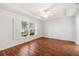 Bright bedroom featuring wood floors, tray ceiling, and a large window with white shutters at 16610 County Line Rd, Umatilla, FL 32784