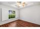 Bedroom featuring hardwood floors, a ceiling fan, and a window overlooking a green lawn at 16610 County Line Rd, Umatilla, FL 32784
