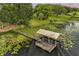 Aerial shot of a boat dock with lift on a tranquil lake surrounded by lily pads and lush trees at 16610 County Line Rd, Umatilla, FL 32784