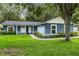 Charming blue single-story home featuring lush green grass and beautiful landscaping at 16610 County Line Rd, Umatilla, FL 32784