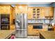 Well-lit kitchen showcasing stainless appliances, wooden cabinets, stone counters, and stone tile backsplash at 16610 County Line Rd, Umatilla, FL 32784