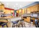 Open kitchen with knotty wood cabinets, an island with seating, stone tile backsplash, and stainless appliances at 16610 County Line Rd, Umatilla, FL 32784