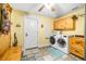 A bright laundry room with a washer and dryer set, wooden cabinets and unique tiled floors at 16610 County Line Rd, Umatilla, FL 32784