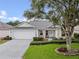 Charming single-story home with manicured lawn, mature trees, and an attached two-car garage at 16950 Se 80Th Bellavista Cir, The Villages, FL 32162