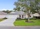 Charming single-story home featuring a well-manicured lawn, mature trees, and a two-car garage at 16950 Se 80Th Bellavista Cir, The Villages, FL 32162