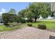 Paver patio with manicured landscaping and golf course views beyond the treeline at 16950 Se 80Th Bellavista Cir, The Villages, FL 32162