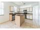 Open kitchen featuring an island, white cabinets, stainless steel microwave, and tile flooring at 2110 Mallard Creek Cir, Kissimmee, FL 34743