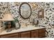 Cozy bathroom with charming floral wallpaper, vanity with lamp and round mirror at 2208 Mcmahon Ct # 1033, Orlando, FL 32812