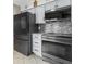 Close-up of the modern kitchen featuring black stainless steel appliances, white cabinets, and tile backsplash at 2936 Estill St, Deltona, FL 32738