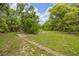 Green backyard with lush trees and an outdoor shed surrounded by grass at 32125 Okaloosa Trl, Sorrento, FL 32776