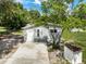 Exterior view of home with a concrete drive, small shed and mature tree in a landscaped yard at 4925 Catfish Rd, Lake Wales, FL 33898