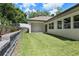 View of backyard featuring a covered patio, green lawn, and retaining wall with landscaping at 523 Sanctuary Golf Pl, Apopka, FL 32712