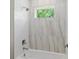 Bright bathroom features a shower/tub combo with white and marble-look tiling and a garden window at 523 Sanctuary Golf Pl, Apopka, FL 32712