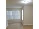 Empty living room with tan walls, tile flooring, and a large window with blinds at 5725 Gatlin Ave # 315, Orlando, FL 32822