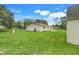 Back of the house features expansive backyard, lush green grass, and mature trees at 6720 Midland Drive, St Cloud, FL 34771