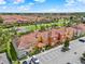 High aerial showcasing the expansive community with lush green spaces, colorful townhomes, and a tranquil lake at 8977 Majesty Palm Rd, Kissimmee, FL 34747