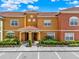 Colorful townhome featuring well-manicured landscaping, tile roofs, and reserved parking for residents at 8977 Majesty Palm Rd, Kissimmee, FL 34747