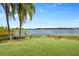 Scenic backyard featuring a putting green and waterfront views with palm trees and lush landscaping at 10300 Pocket Ln, Orlando, FL 32836