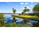 Lush green backyard leading to a tranquil waterfront view with a home in the background, with tropical vegetation at 10300 Pocket Ln, Orlando, FL 32836