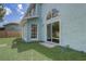 View of the aqua-colored home's backyard, showcasing a sliding glass door and several windows at 10599 Satinwood Cir, Orlando, FL 32825