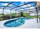 Screened in kidney shaped pool featuring a view of the well-manicured backyard and bright blue sky at 1165 Indian Ridge E Trl, Kissimmee, FL 34747