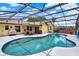 View of the enclosed kidney shaped pool with patio furniture, outdoor lighting, and mature landscaping at 1165 Indian Ridge E Trl, Kissimmee, FL 34747