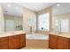 Elegant bathroom featuring a large soaking tub, dual vanities, and natural light at 12868 Holdenbury Ln, Windermere, FL 34786
