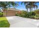 A two car garage with driveway and tropical plants in the backyard at 12868 Holdenbury Ln, Windermere, FL 34786