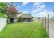 A view of the green backyard with a screened patio and wooden fence, under a partly cloudy sky at 1301 Winter Green Way, Winter Garden, FL 34787